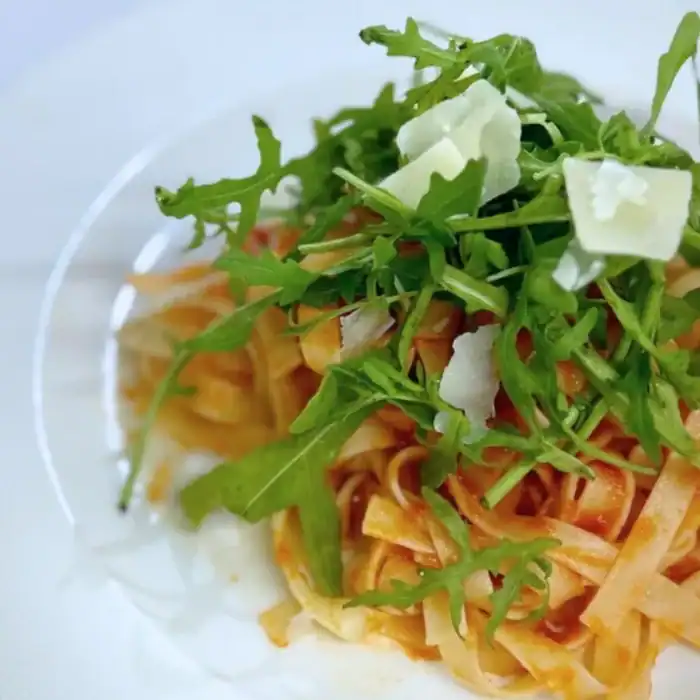 Fresh arugula and Parmesan cheese topping gourmet pasta at The Ro Hotel.