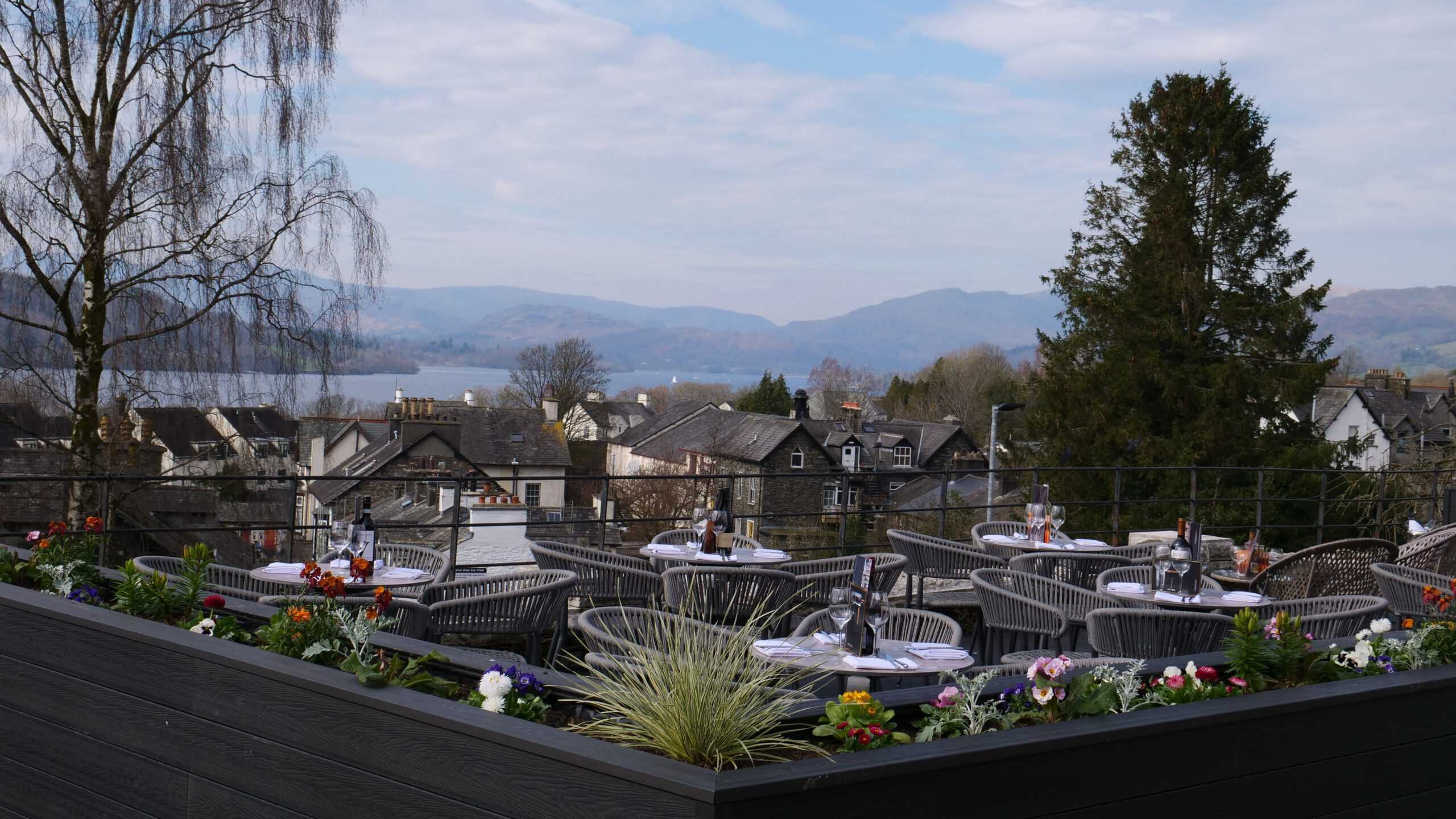 Cozy outdoor rooftop dining with scenic lake and mountain views at The Ro Hotel, perfect for relaxation.