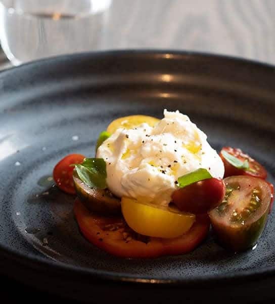Fresh tomato salad with mozzarella and basil at The Ro Hotel restaurant, showcasing gourmet dining and culinary excellence.