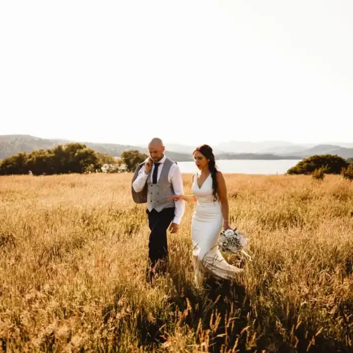 Romantic couple walking through golden field near The Ro Hotel for a scenic countryside wedding.