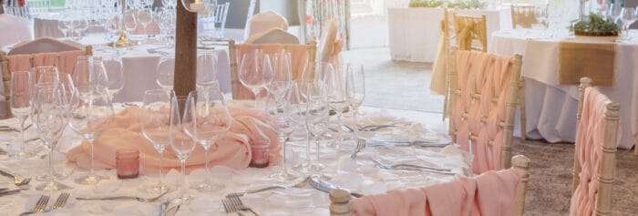Elegant wedding reception setup with tables, glassware, and pink accents at The Ro Hotel.