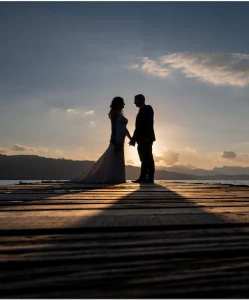 Romantic couple holding hands on a sunset dock at The Ro Hotel, perfect for a special getaway.