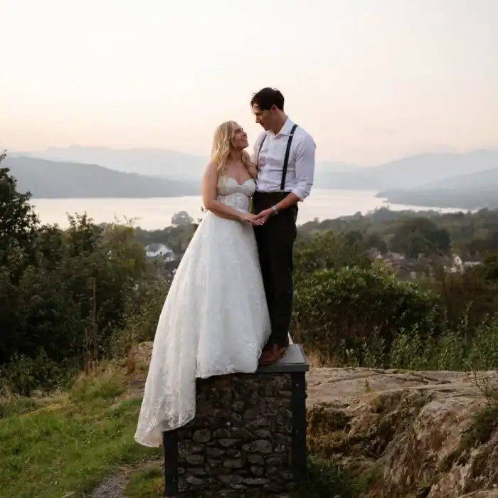 Romantic bride and groom on scenic overlook with lake views and mountains in background.