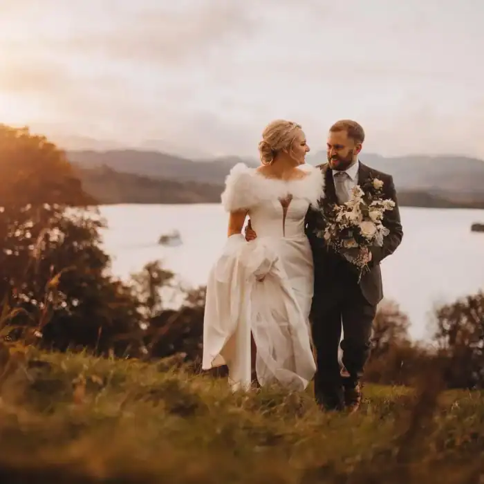 Elegant wedding couple walking outdoors by a lake at sunset, romantic atmosphere, The Ro Hotel destination wedding venue.