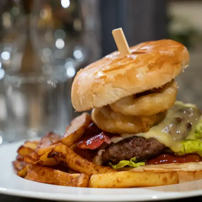 Juicy gourmet burger with crispy fries and fresh toppings at The Ro Hotel.